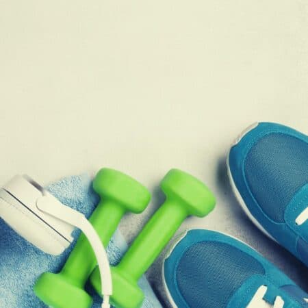 exercise trainers and weights with headphones on plain background